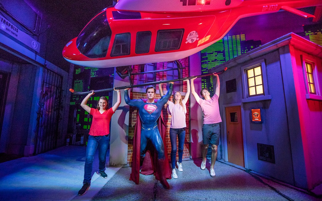 Visitors posing with Superman figure at Madame Tussauds Sydney, part of the Multi Attraction Pass.