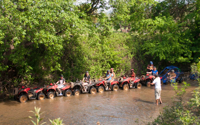 Quad riders navigating a shallow stream during a safari in Antalya.