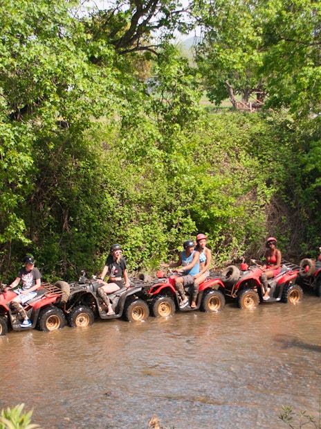 Quad riders navigating a shallow stream during a safari in Antalya.