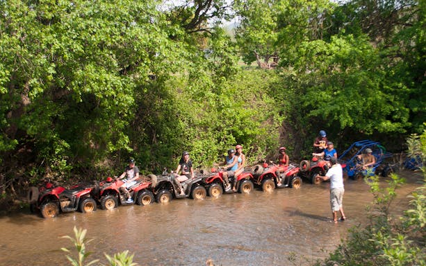 Quad riders navigating a shallow stream during a safari in Antalya.
