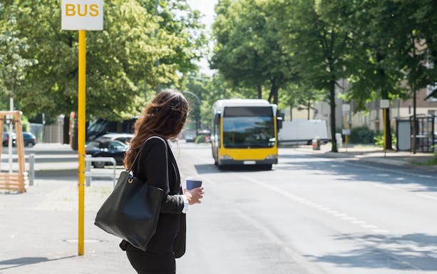 Tourist waiting at a bus stop in Barcelona with Hola Barcelona Travel Card.