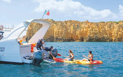 Kayakers departing from a boat near Ponta da Piedade cliffs, Algarve.