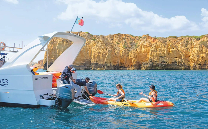 Kayakers departing from a boat near Ponta da Piedade cliffs, Algarve.