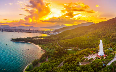 Aerial view of Sơn Trà Peninsula with Lady Buddha statue at sunset, Đà Nẵng, Vietnam.
