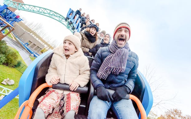 Family enjoying a roller coaster ride at Parc Asterix during Christmas celebrations.