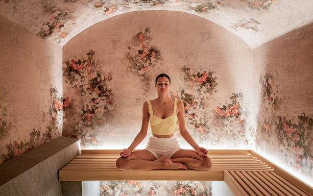 Person meditating in a floral-themed relaxation room at QC Terme Milano.