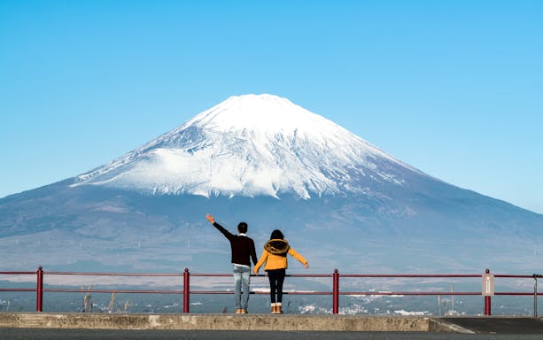 Couple admiring Mt. Fuji from Kawaguchiko viewpoint on a clear day.