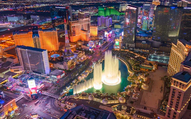 Aerial view of Las Vegas Strip at night with illuminated fountains and hotels.