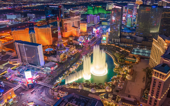 Aerial view of Las Vegas Strip at night with illuminated fountains and hotels.