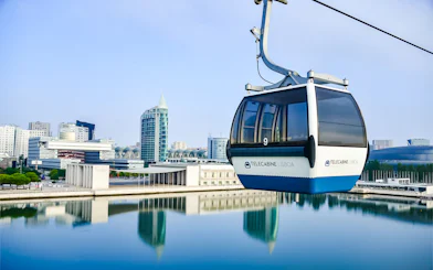 Lisbon cable car over water with cityscape in background.