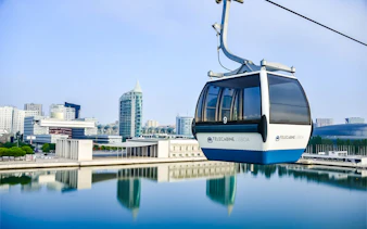 Lisbon cable car over water with cityscape in background.