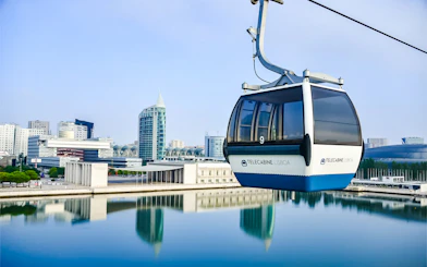 Lisbon cable car over water with cityscape in background.