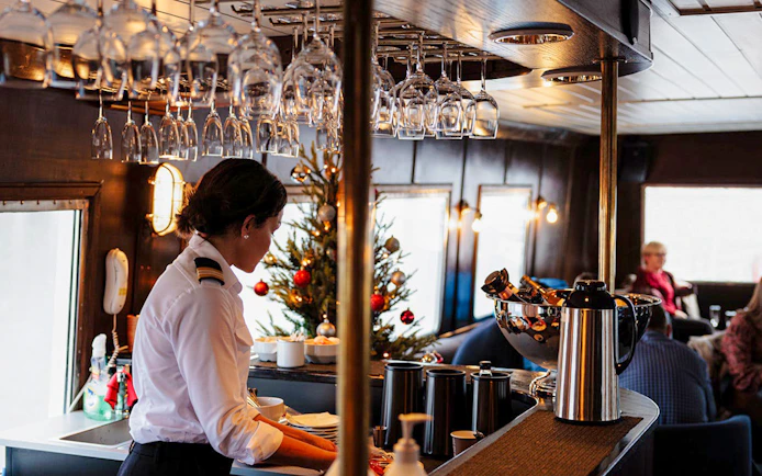 Server preparing drinks on Ålesund-Geiranger-Ålesund Fjord boat tour.