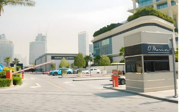 Entrance to Marasi Marina in Dubai with modern buildings and parked cars.