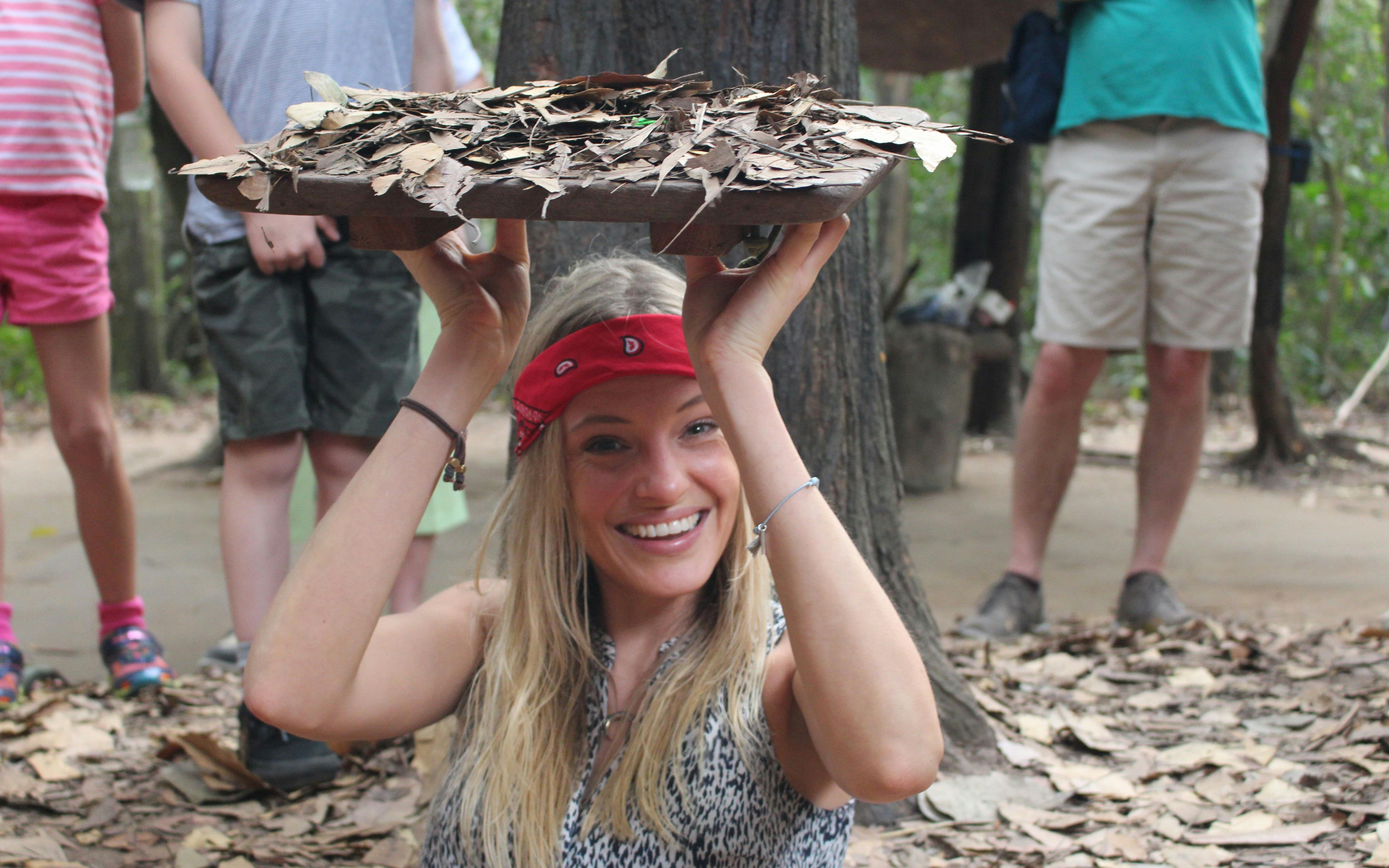 Tourist demonstrating Cu Chi Tunnels entrance during VIP PREMIUM tour in Vietnam.