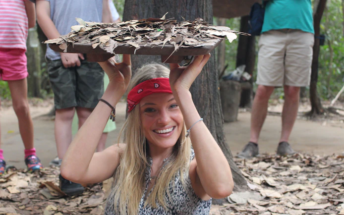 Tourist demonstrating Cu Chi Tunnels entrance during VIP PREMIUM tour in Vietnam.