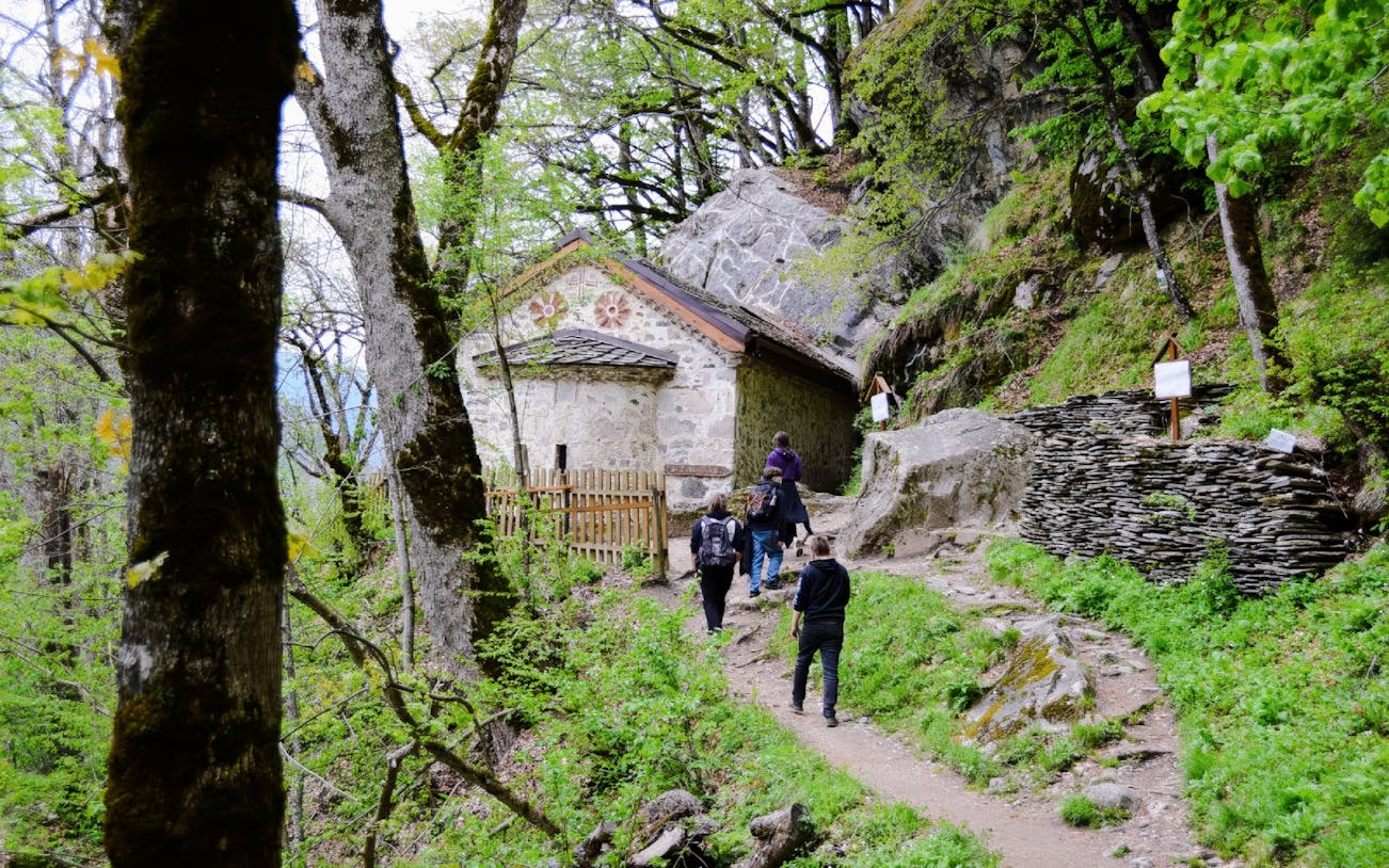 Guests walking towards St. Ivan Cave through a forested path.