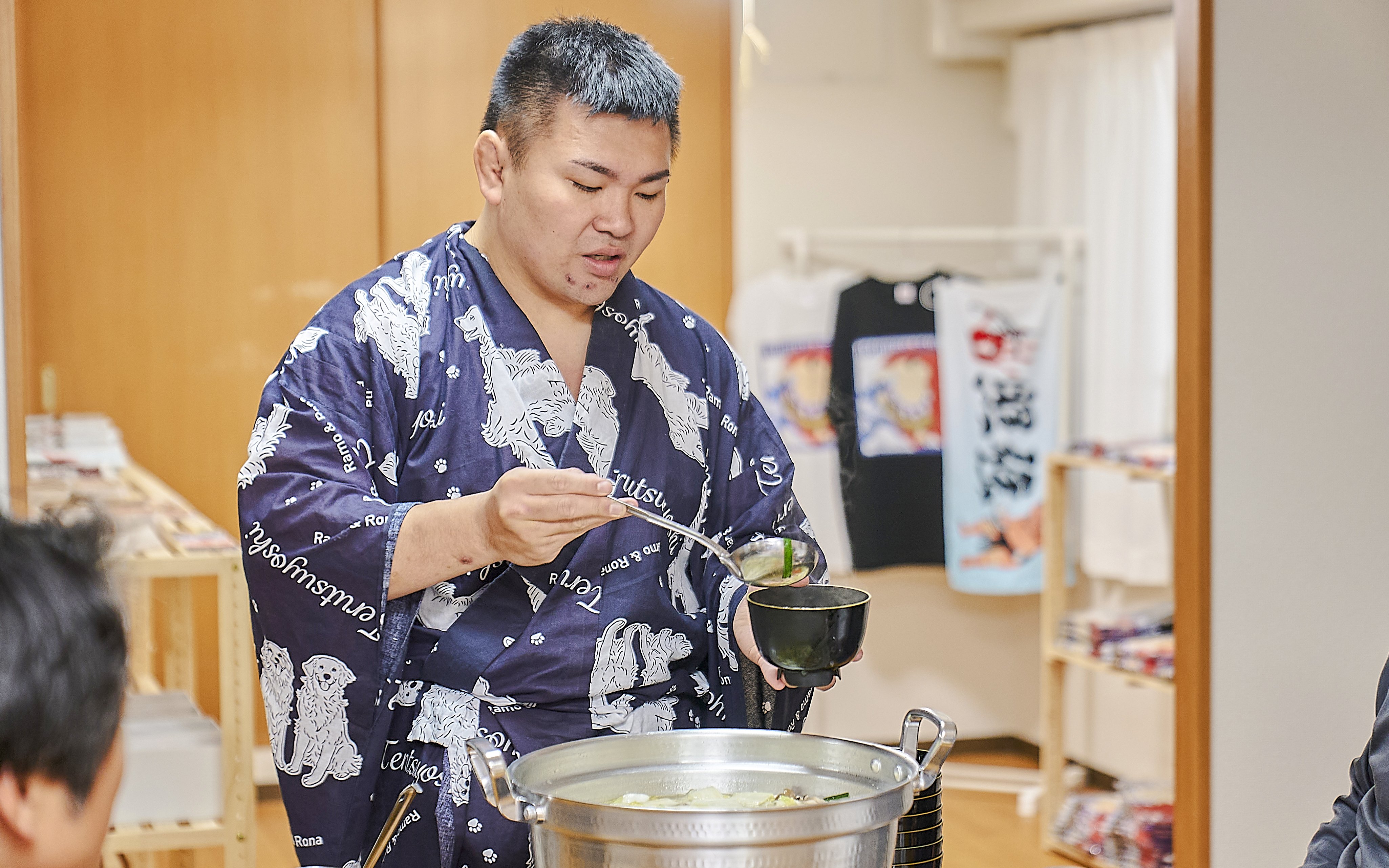 Sumo wrestler serving soup during a Koto City sumo show experience.