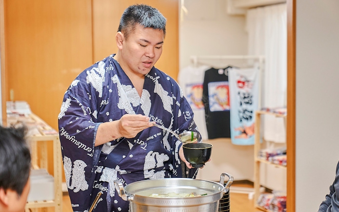 Sumo wrestler serving soup during a Koto City sumo show experience.