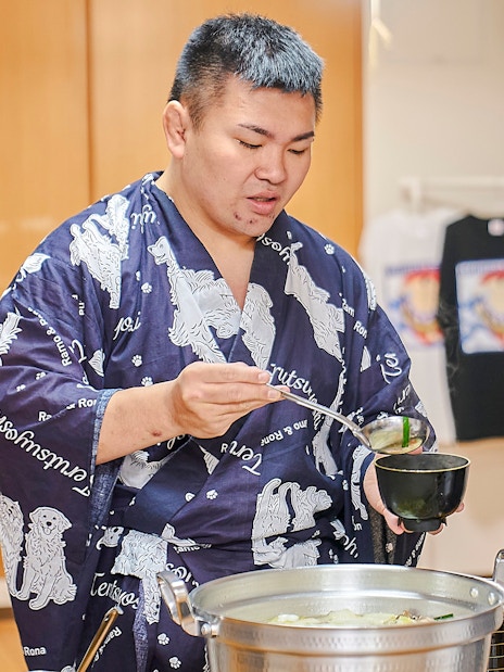 Sumo wrestler serving soup during a Koto City sumo show experience.