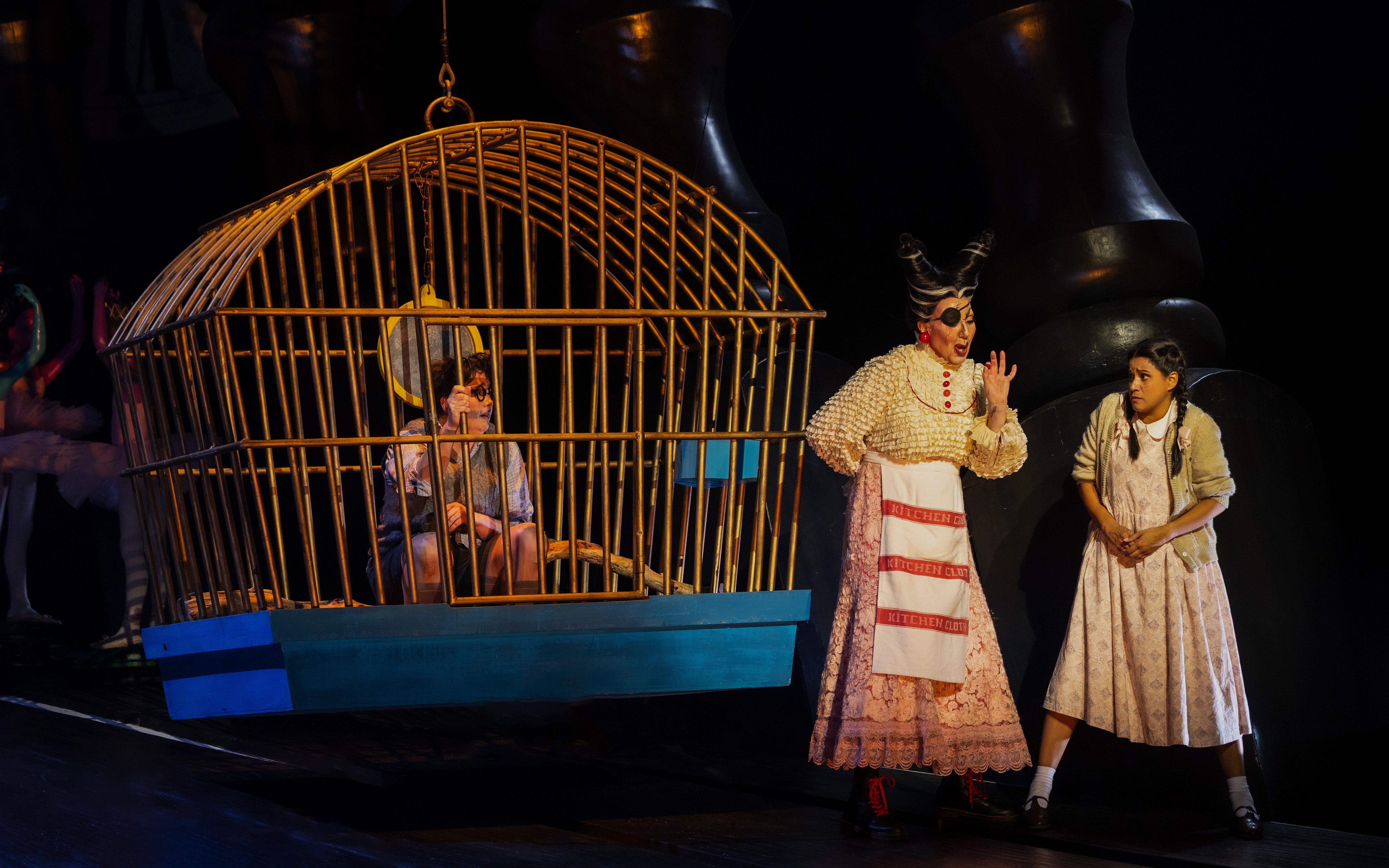 Hansel in a cage and Gretel with a witch during a stage performance of Hansel and Gretel.