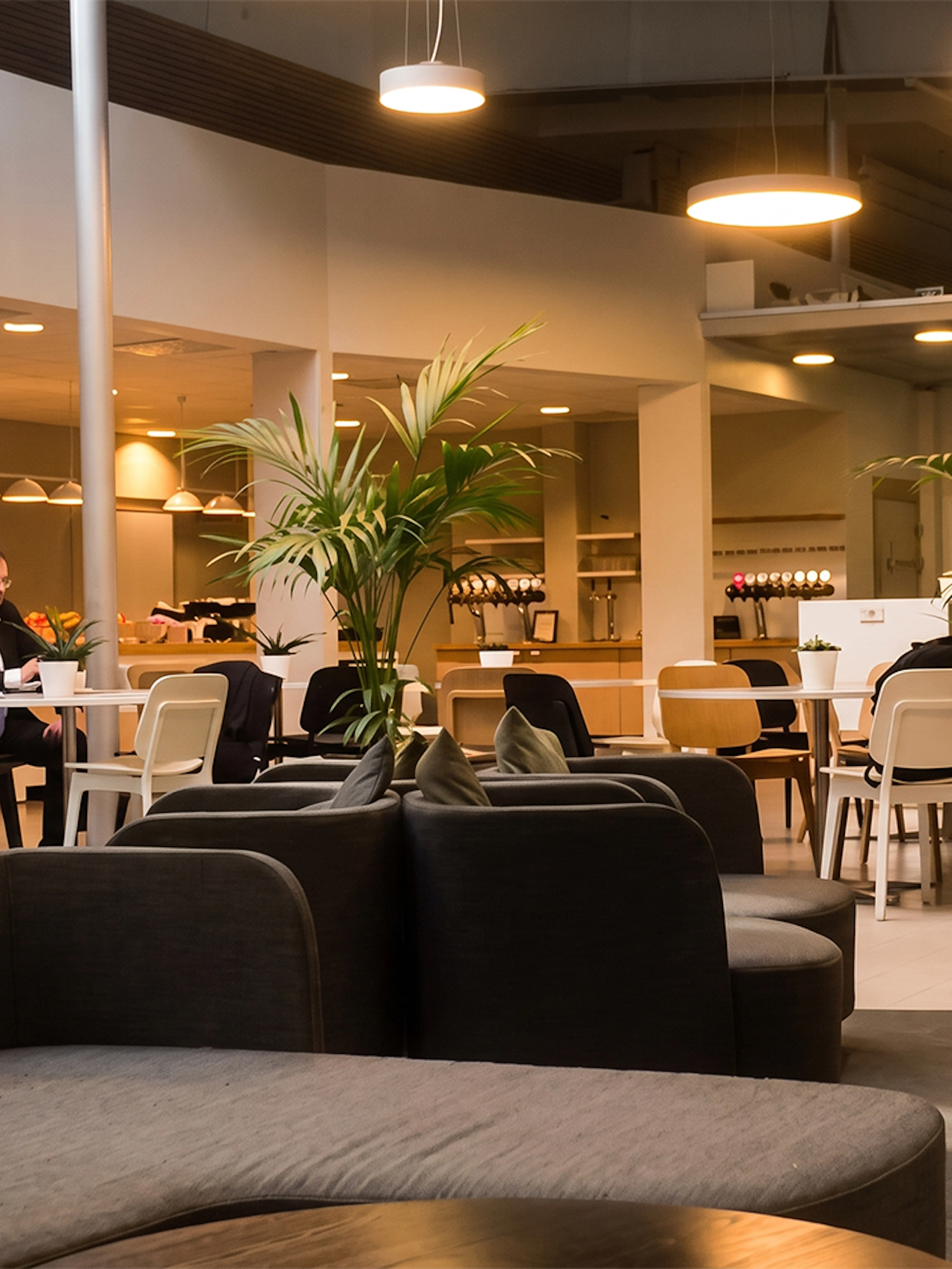 Pearl Lounge seating area with tables and plants at Stockholm Arlanda Airport Terminal 2.