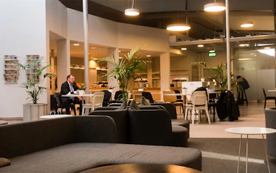 Pearl Lounge seating area with tables and plants at Stockholm Arlanda Airport Terminal 2.