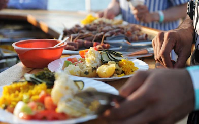 Tourist enjoying lunch on catamaran with plates of colorful food.