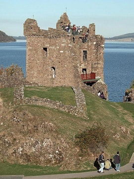 Urquhart Castle overlooking Loch Ness with visitors exploring the ruins.