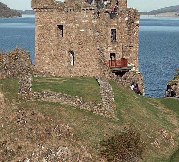 Urquhart Castle overlooking Loch Ness with visitors exploring the ruins.
