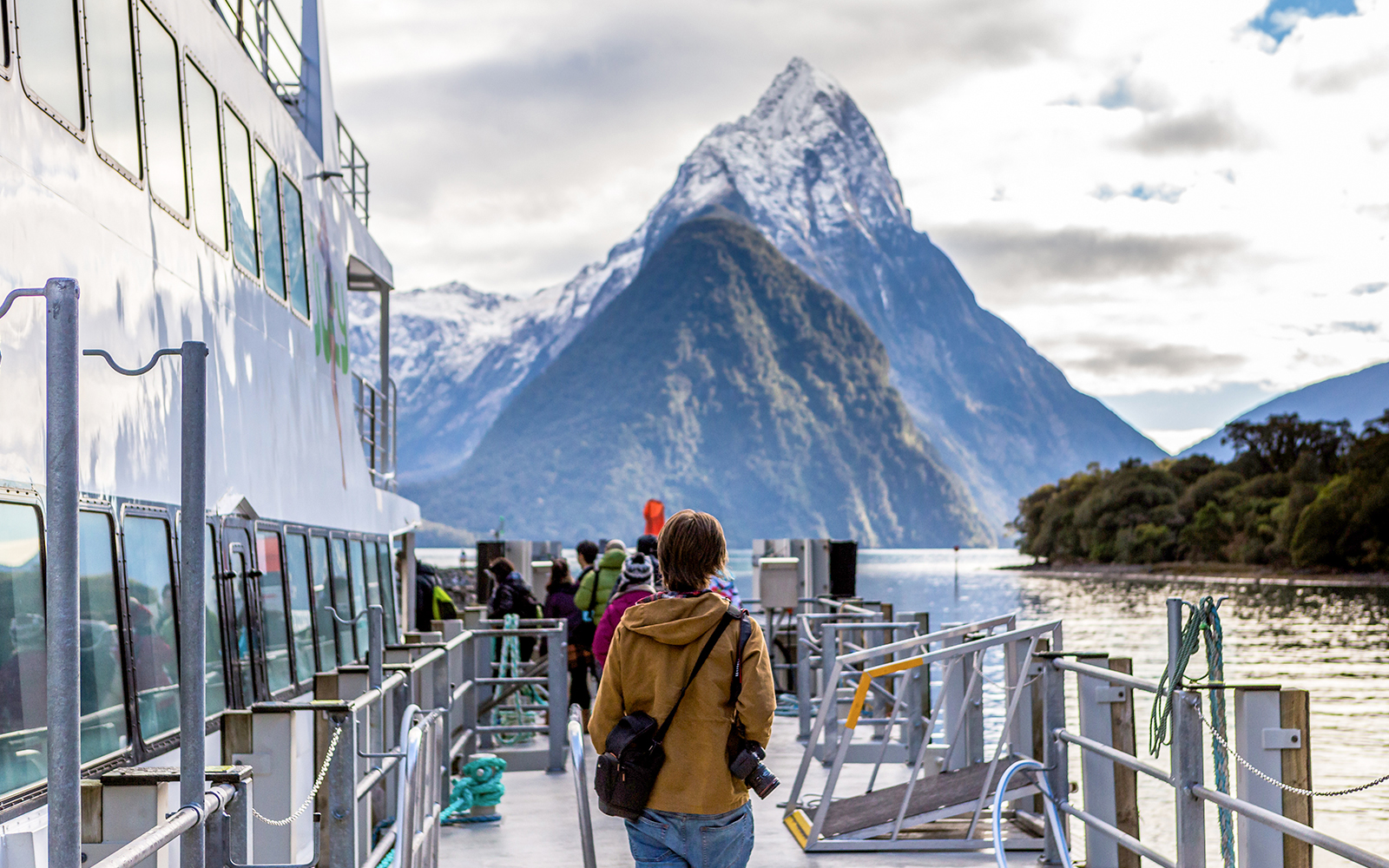 Cruise passengers on deck with view of Mitre Peak, Milford Sound, New Zealand.