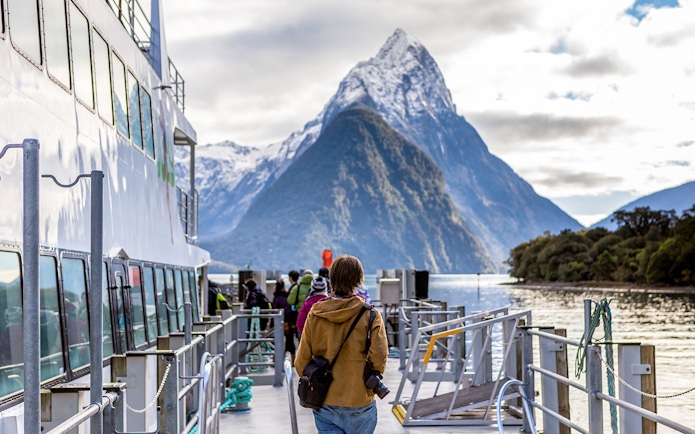 Cruise passengers on deck with view of Mitre Peak, Milford Sound, New Zealand.