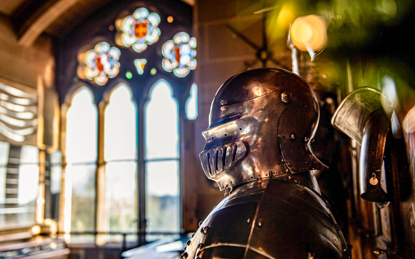Knight's armor inside Warwick Castle with stained glass window in the background.