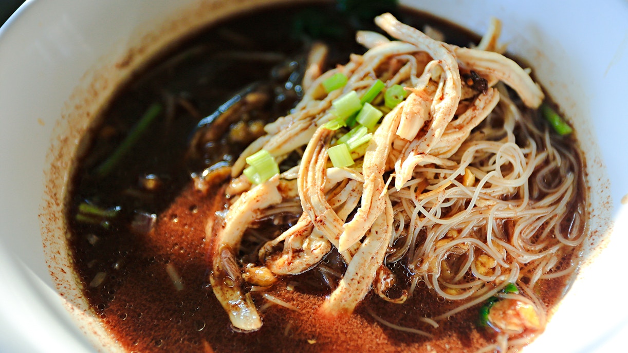 Boat noodles with Phak Wan in Ayutthaya, featuring sliced meat and green onions.