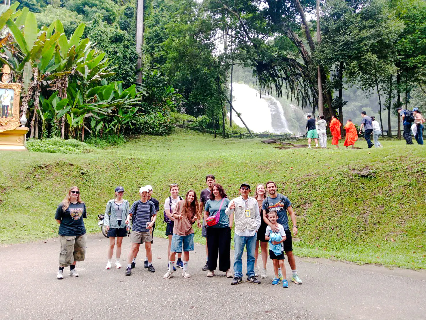 Group of tourists at Doi Inthanon with waterfall and monks in background, Chiang Mai.
