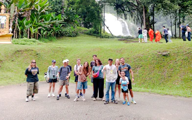 Group of tourists at Doi Inthanon with waterfall and monks in background, Chiang Mai.
