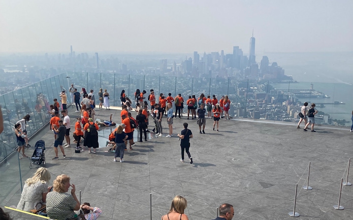 Visitors at Edge Observation Deck in NYC overlooking Manhattan skyline.