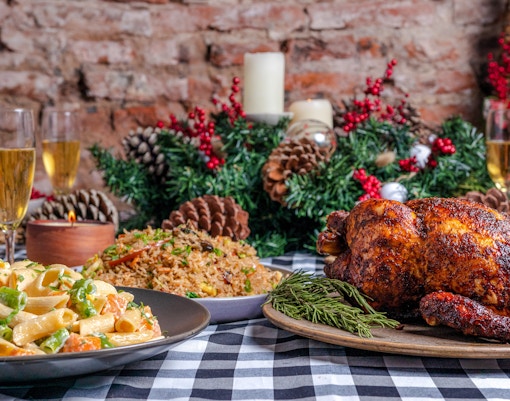 Creole Christmas meal with roasted chicken, pasta, and rice on a festive table setting.