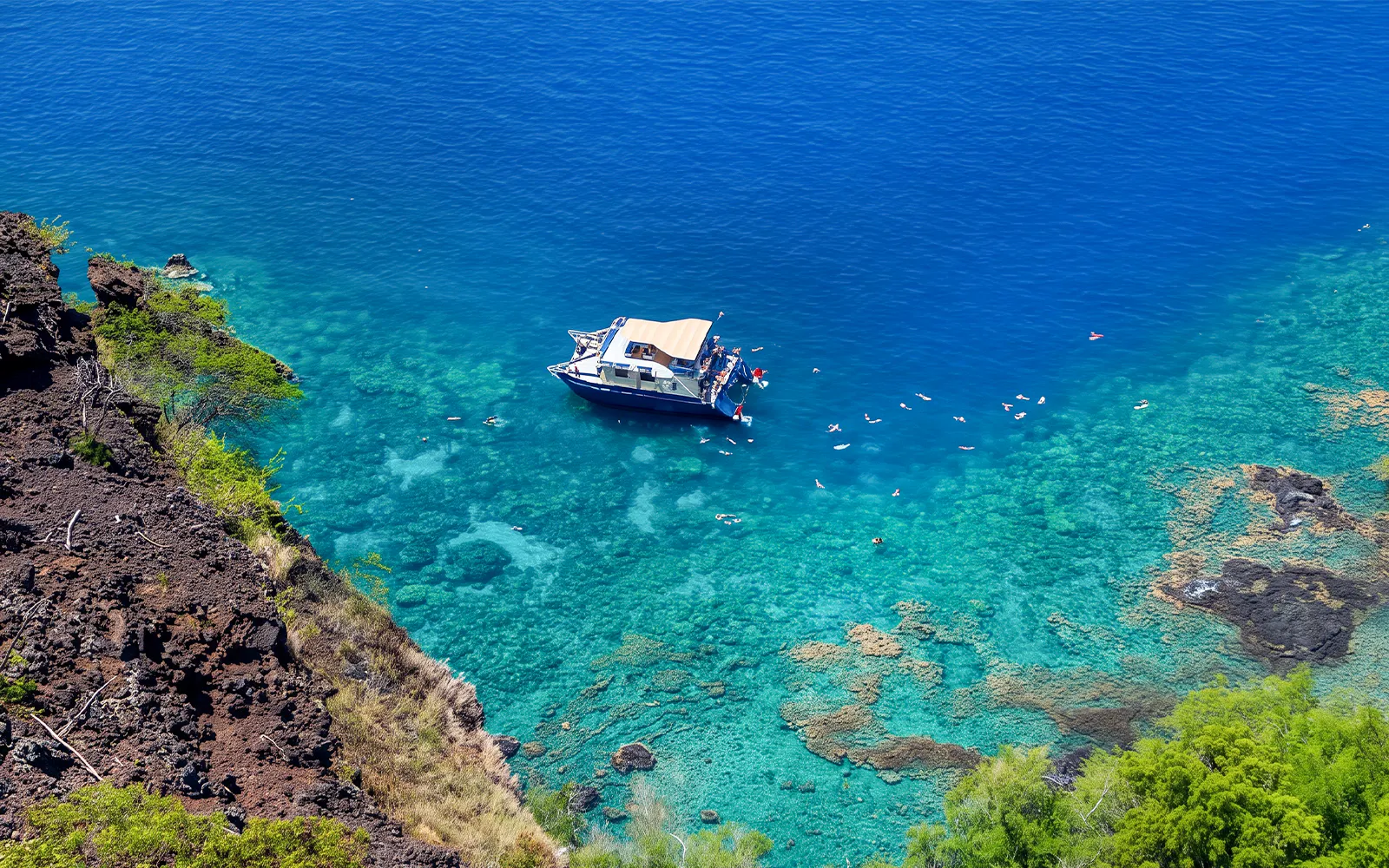 Boat anchored in Kealakekua Bay with snorkelers exploring the clear waters.