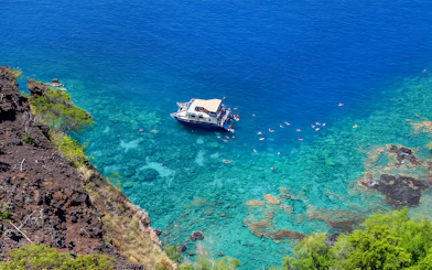Boat anchored in Kealakekua Bay with snorkelers exploring the clear waters.