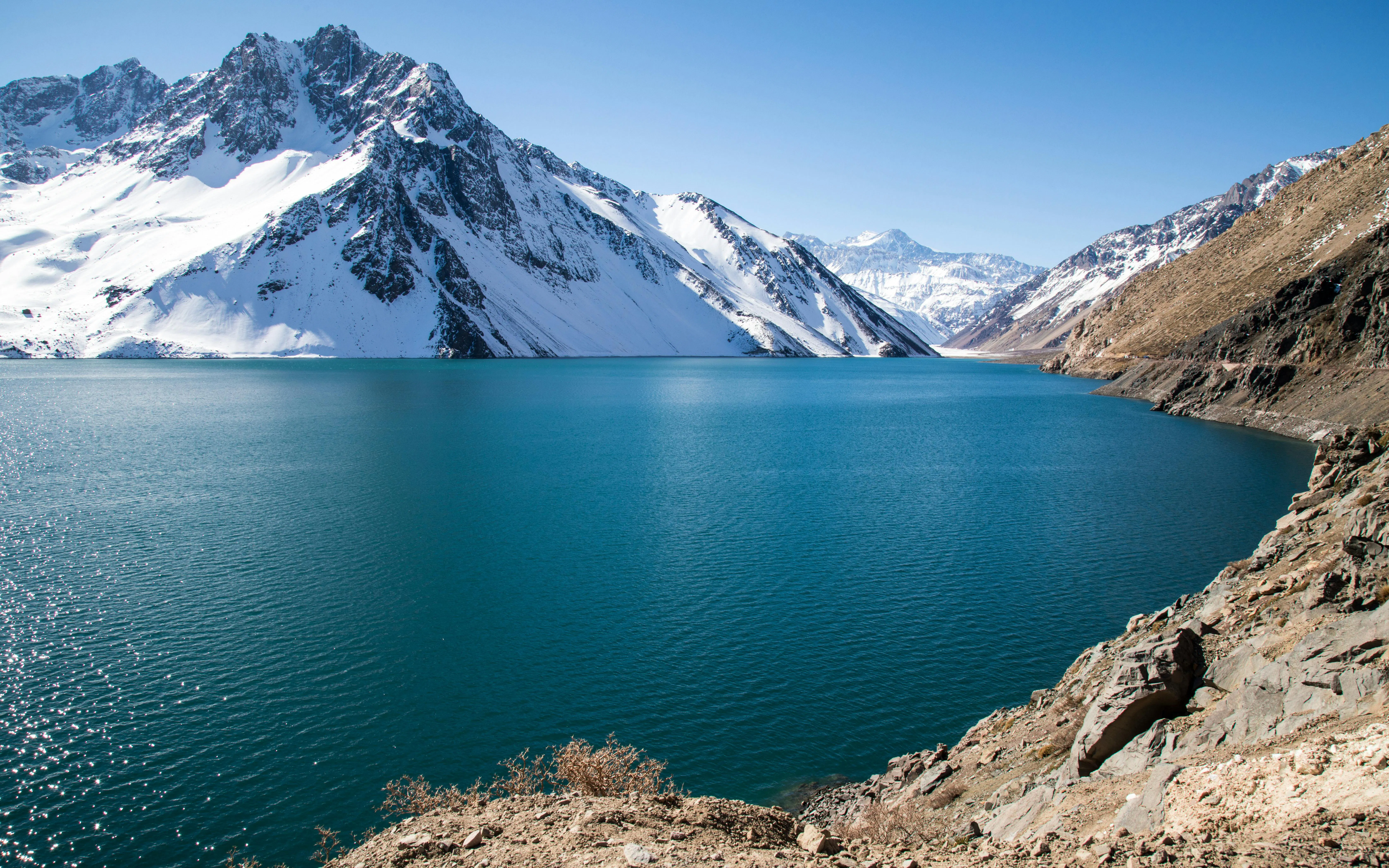 Snow-capped Andes mountains surrounding Embalse El Yeso reservoir in Chile.