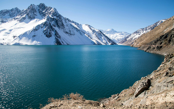 Snow-capped Andes mountains surrounding Embalse El Yeso reservoir in Chile.