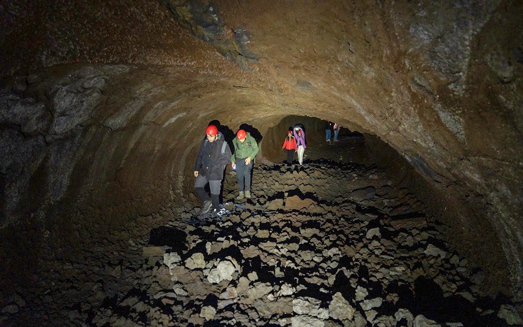 Tourists exploring a lava cave during the Etna Morning Tour in Catania.