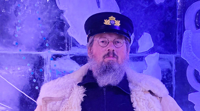 Man in captain's hat holding a beer at Berlin Icebar with ice sculptures in the background.