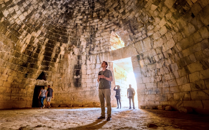 Visitors inside the ancient tomb at Mycenae, Peloponnese, Greece.