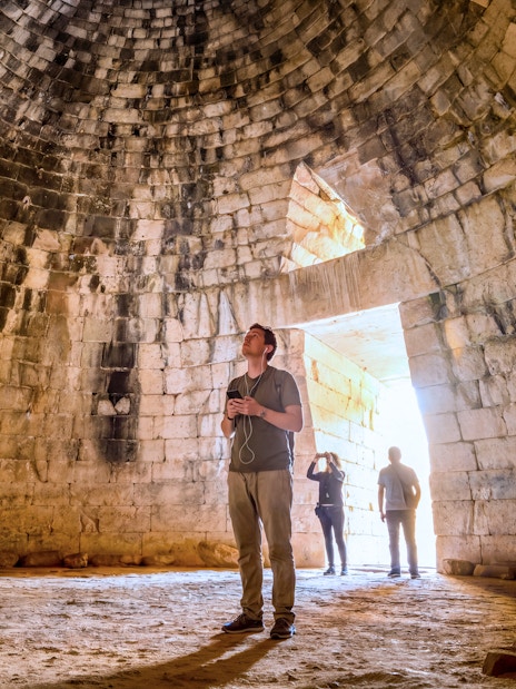 Visitors inside the ancient tomb at Mycenae, Peloponnese, Greece.