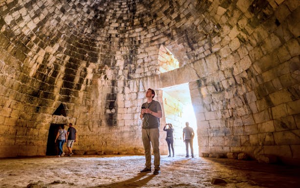 Visitors inside the ancient tomb at Mycenae, Peloponnese, Greece.