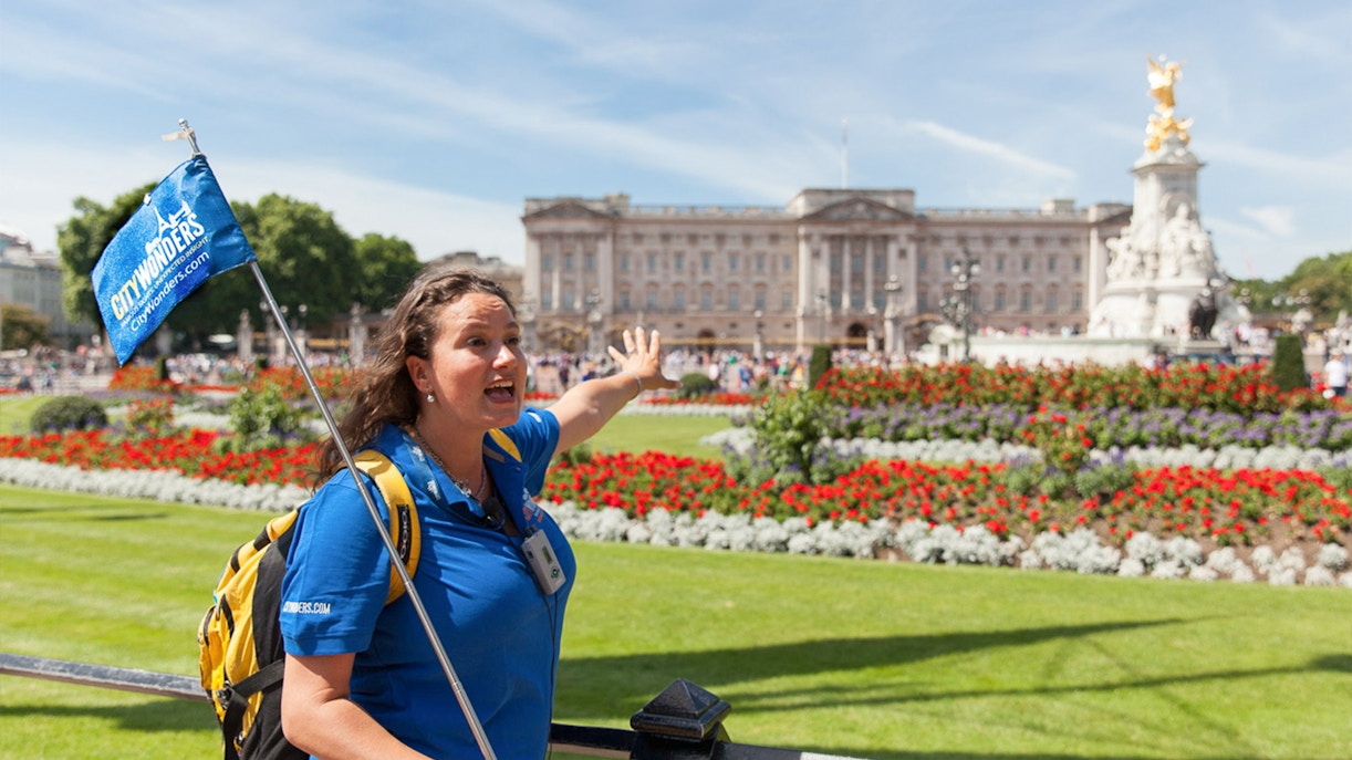 Tour guide with City Wonders flag in front of Buckingham Palace, London.