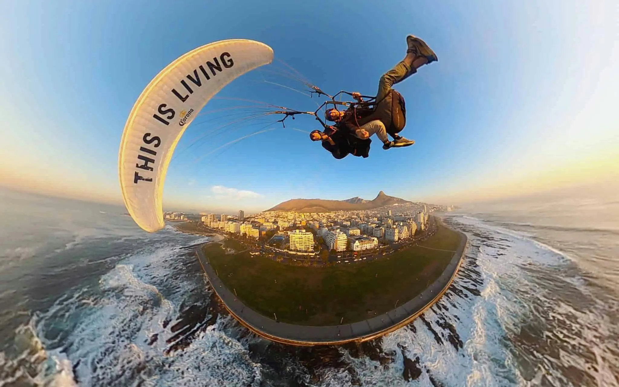 Tandem paragliding over Cape Town coastline with city and mountains in view.