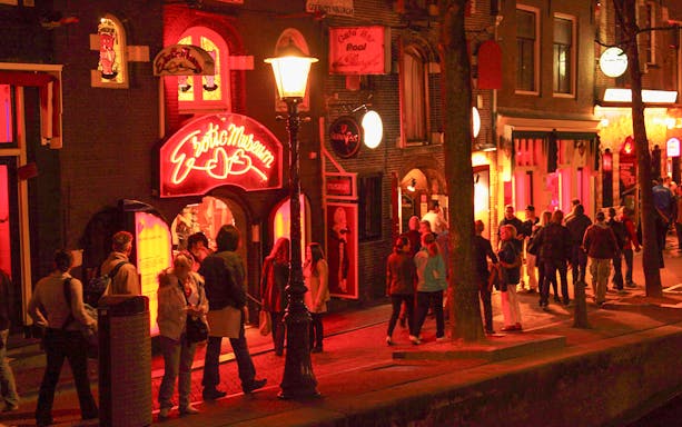 Evening view of Amsterdam's Red-Light District with people near the Erotic Museum.